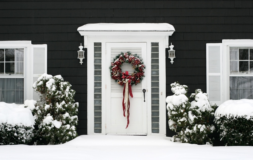 house front door in the snow w a holiday wreath